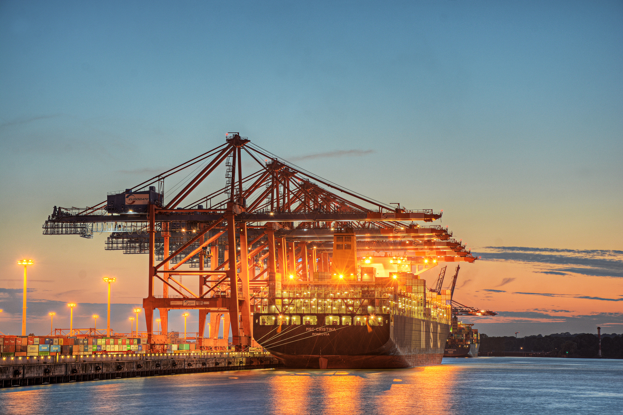 Ein Containerschiff liegt in der Abenddämmerung vor dem Hamburger Hafen